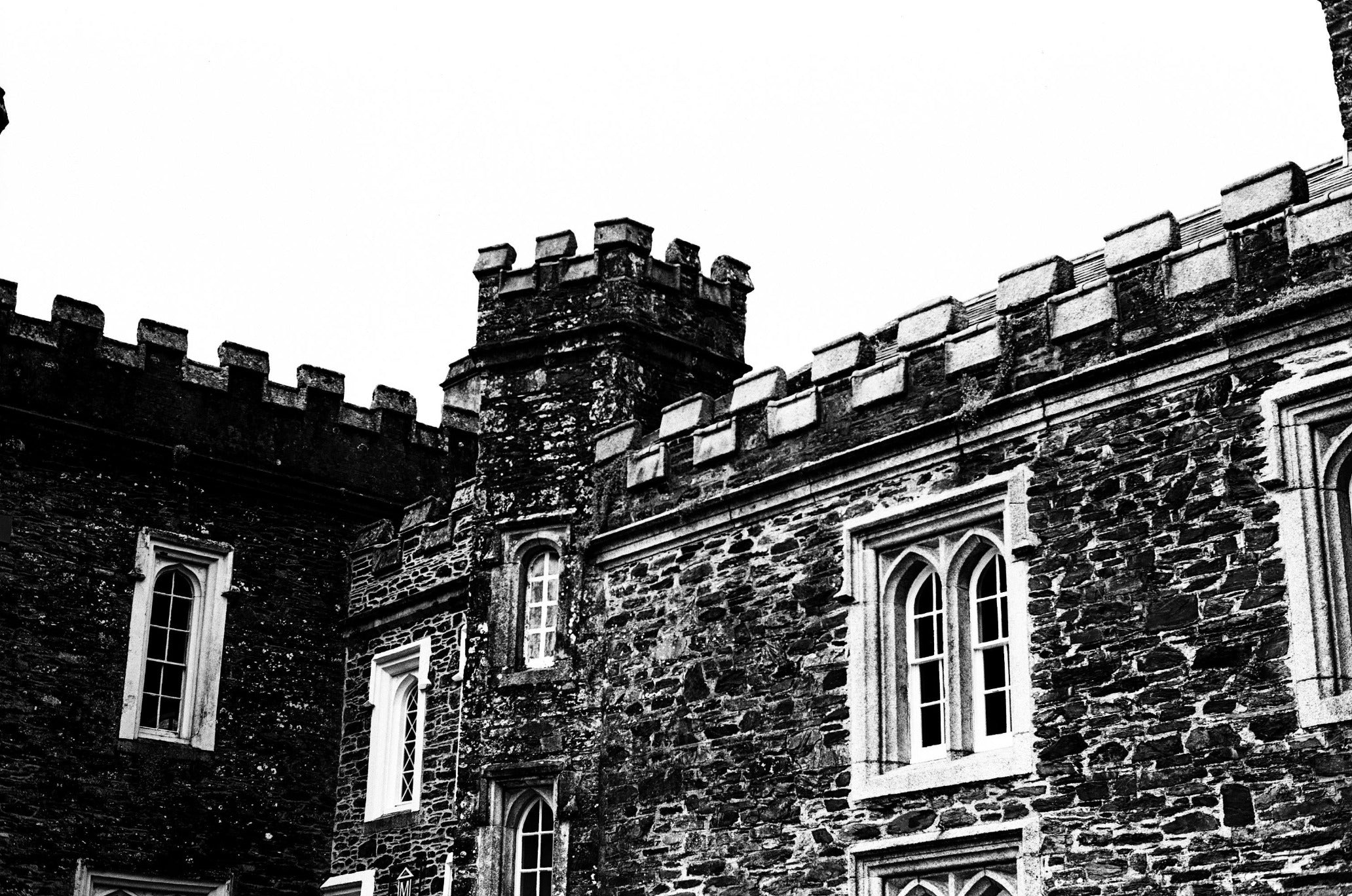 Black and white image of a castle-like building with stone walls and battlements.