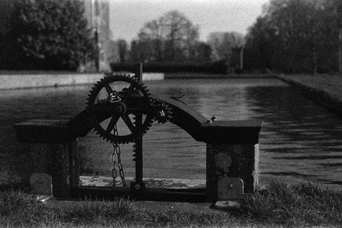 Mechanical sculpture with gears by a body of water