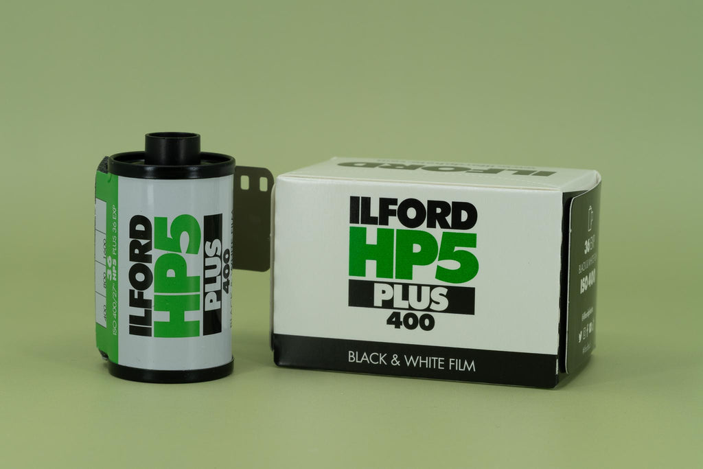 Ilford HP5 Plus 400 black and white film canister and packaging on a green background