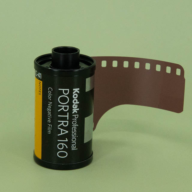 Kodak Portra 160 film canister with a strip of film on a green background