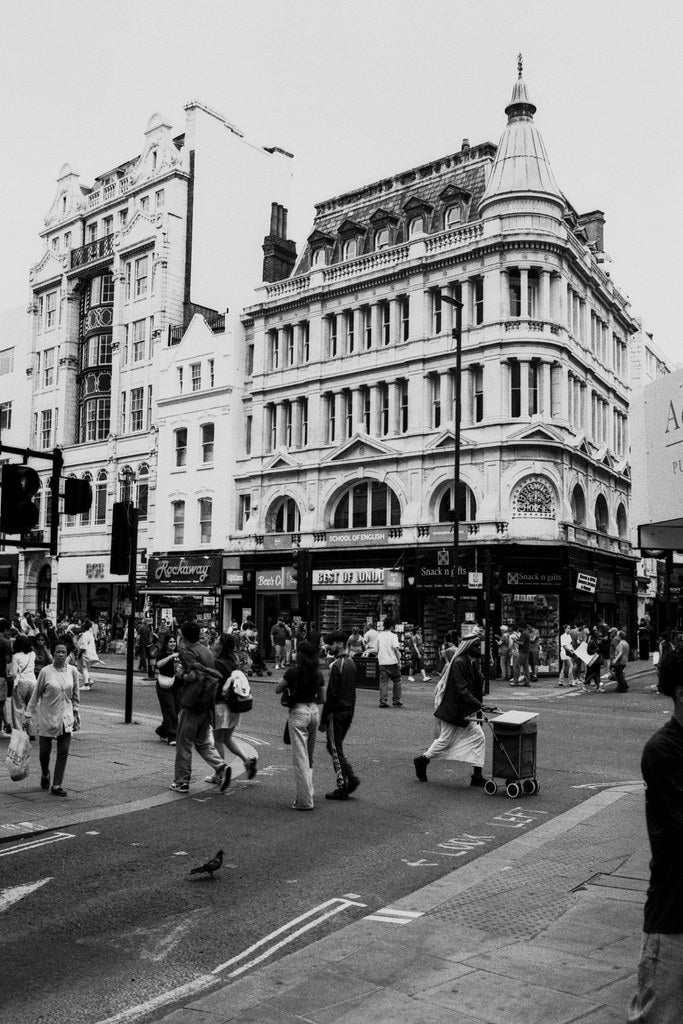 Black and white street scene with pedestrians and historic buildings in an urban setting
