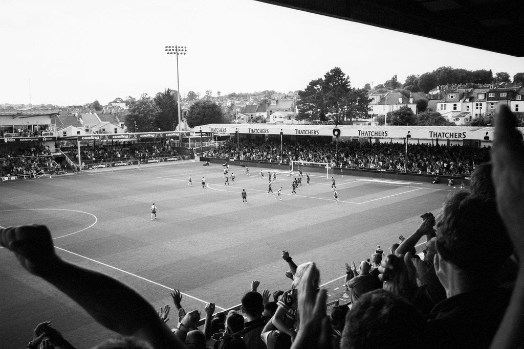 Soccer match in progress with fans in the stands, black and white photo.