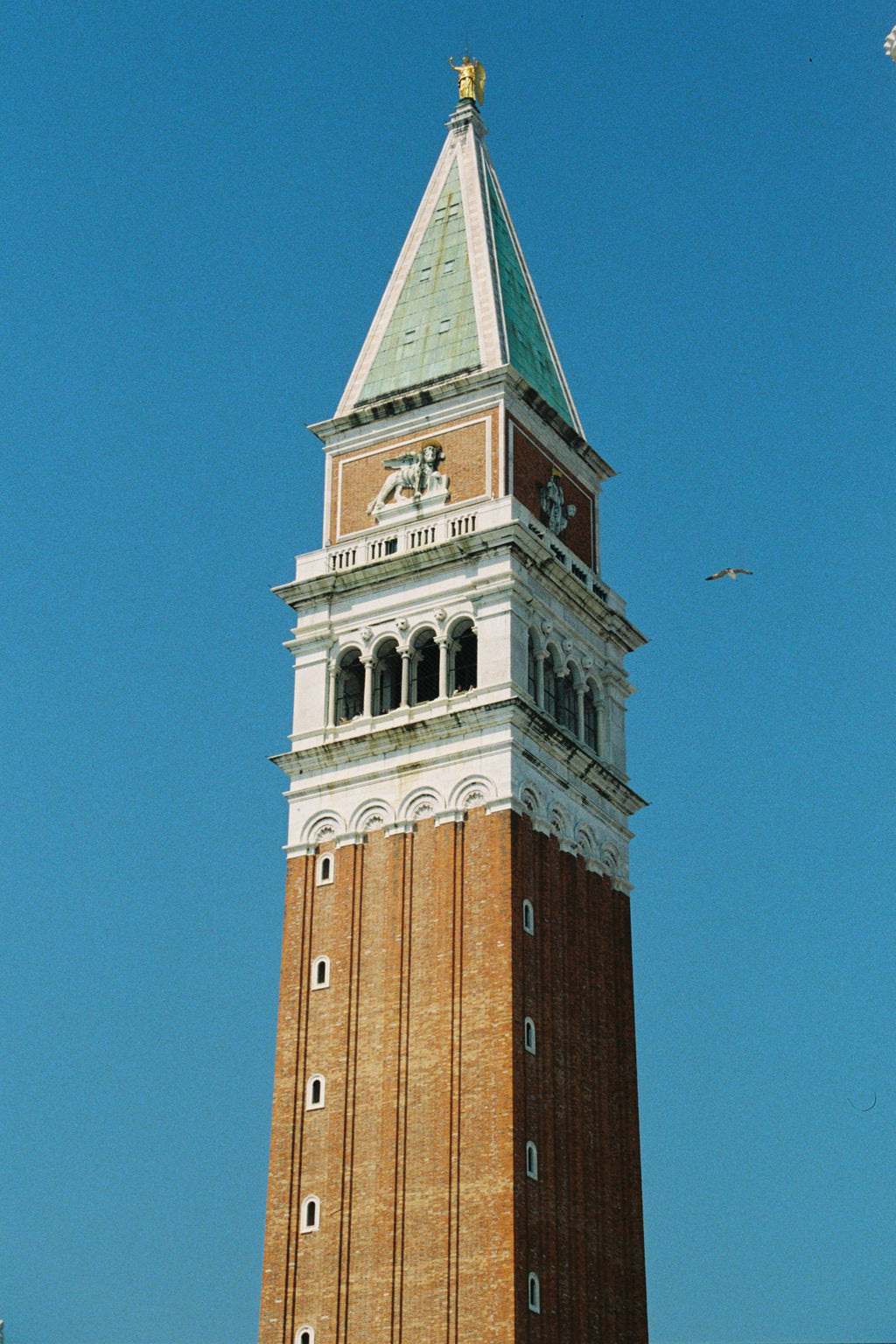 Bell tower with a green roof against a clear blue sky