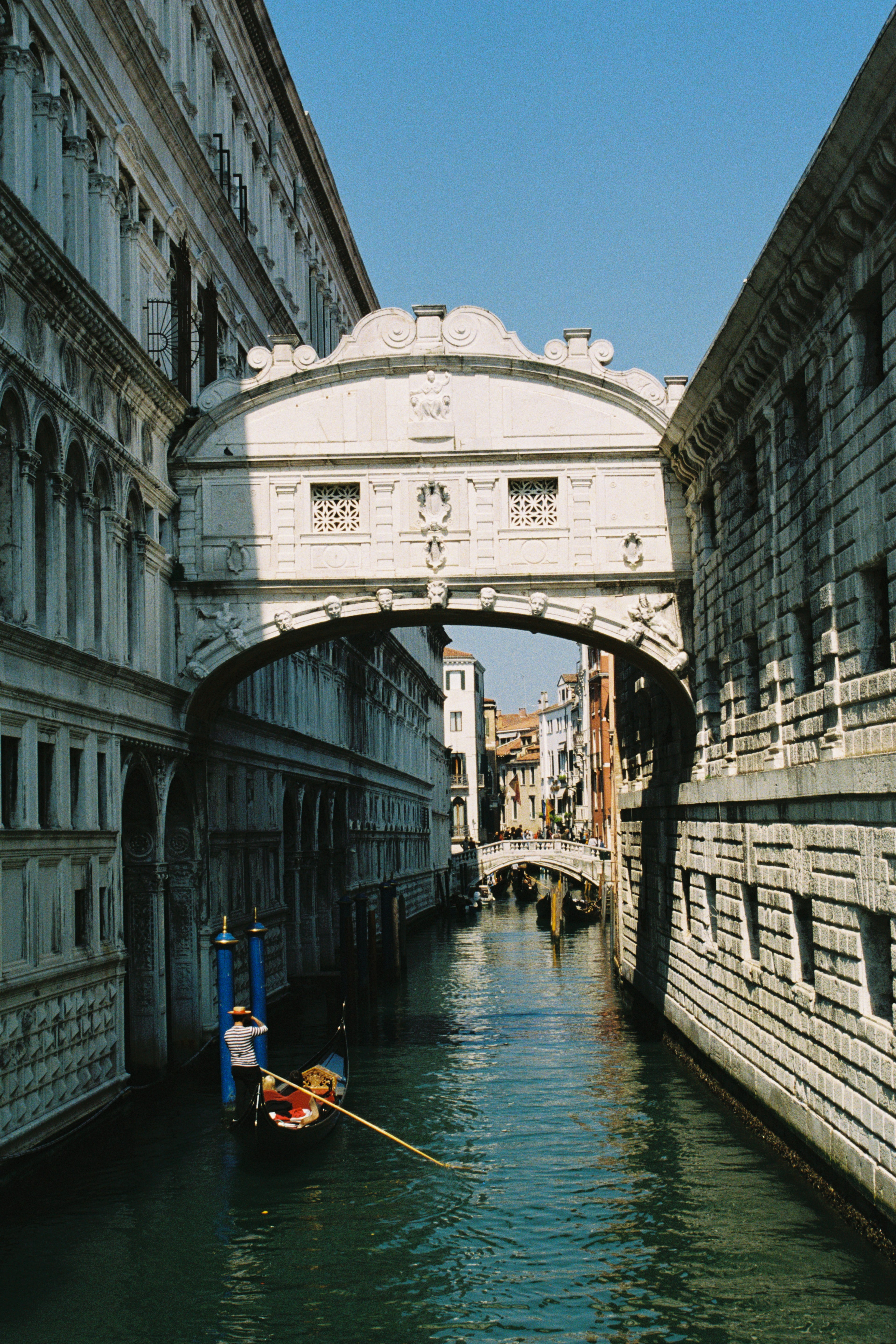 Man on a boat under a bridge with a clear blue sky