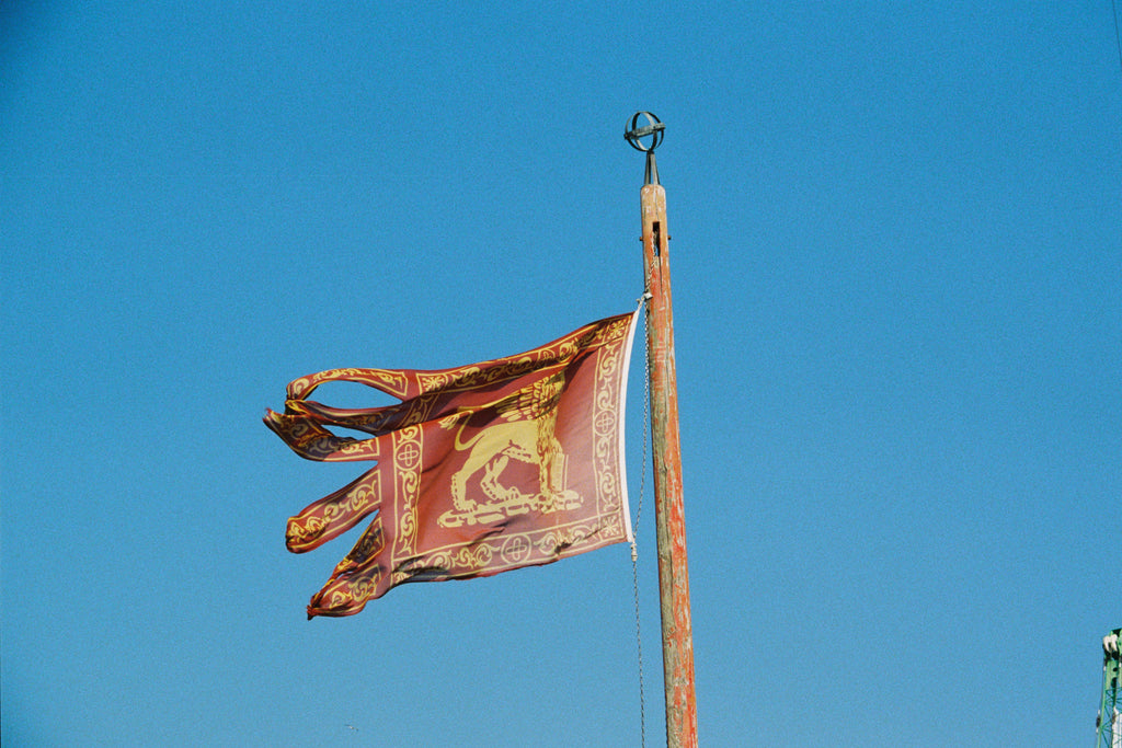 Decorative flag on a pole against a clear blue sky