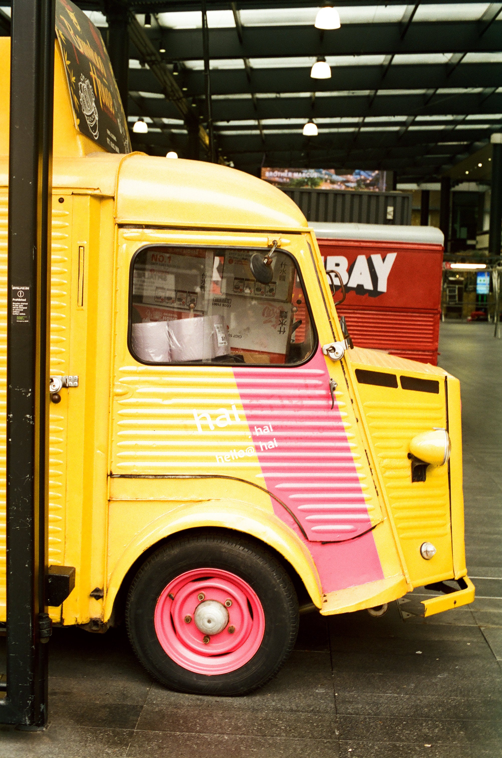 Yellow and pink truck with a red building in the background