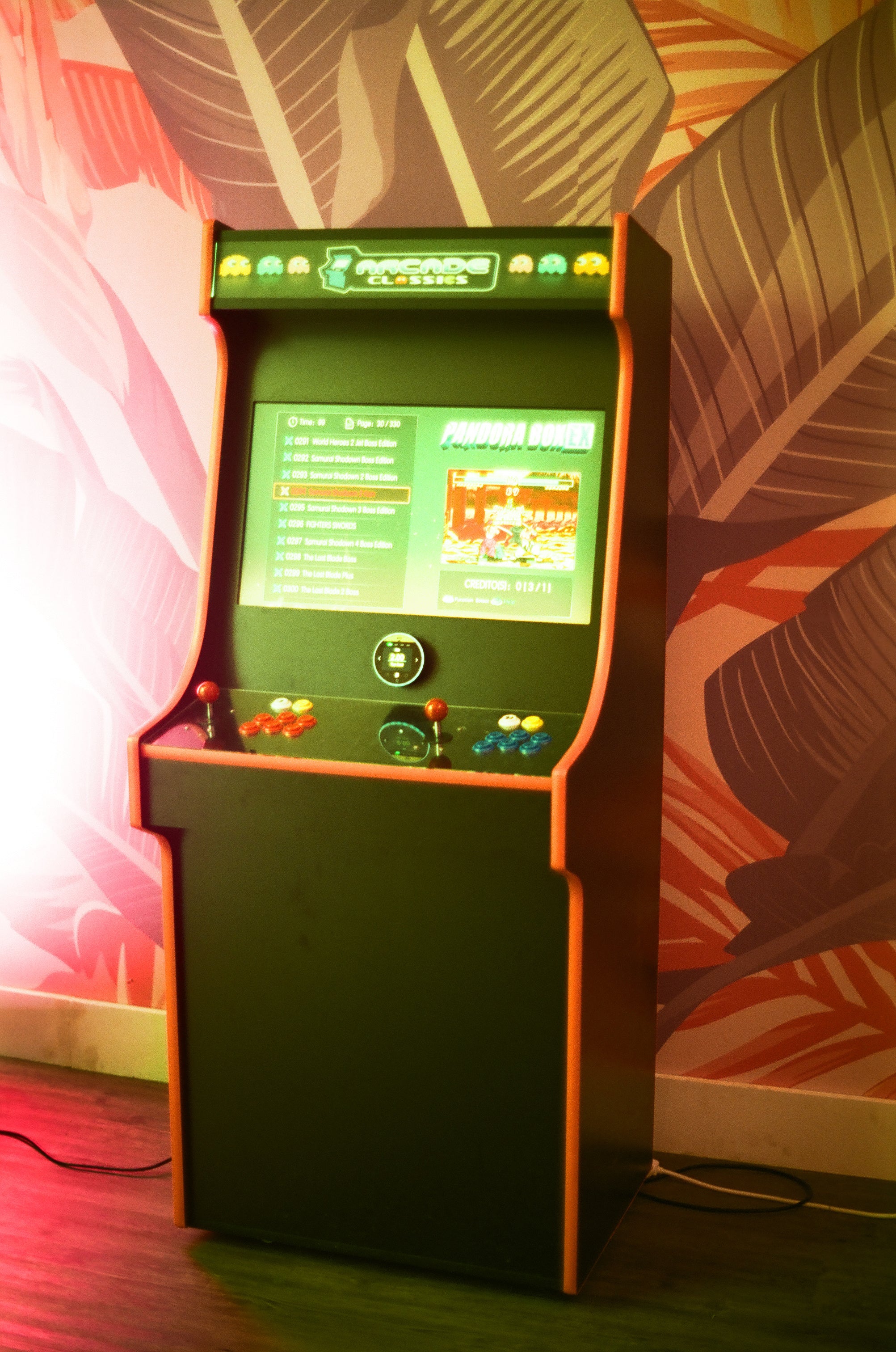 Vintage arcade machine with a green screen against a colorful wall.