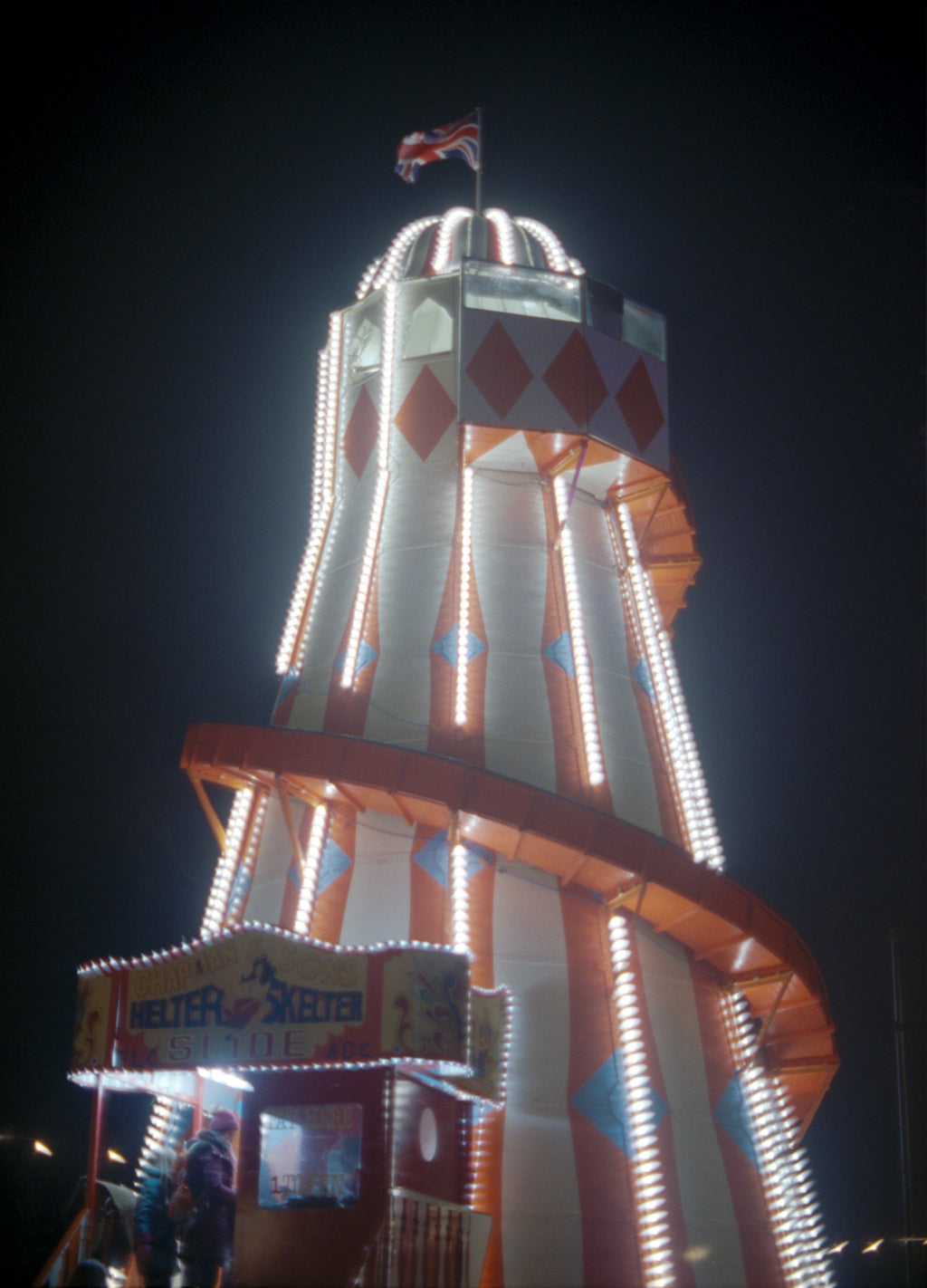Decorative tower with lights and a flag at night