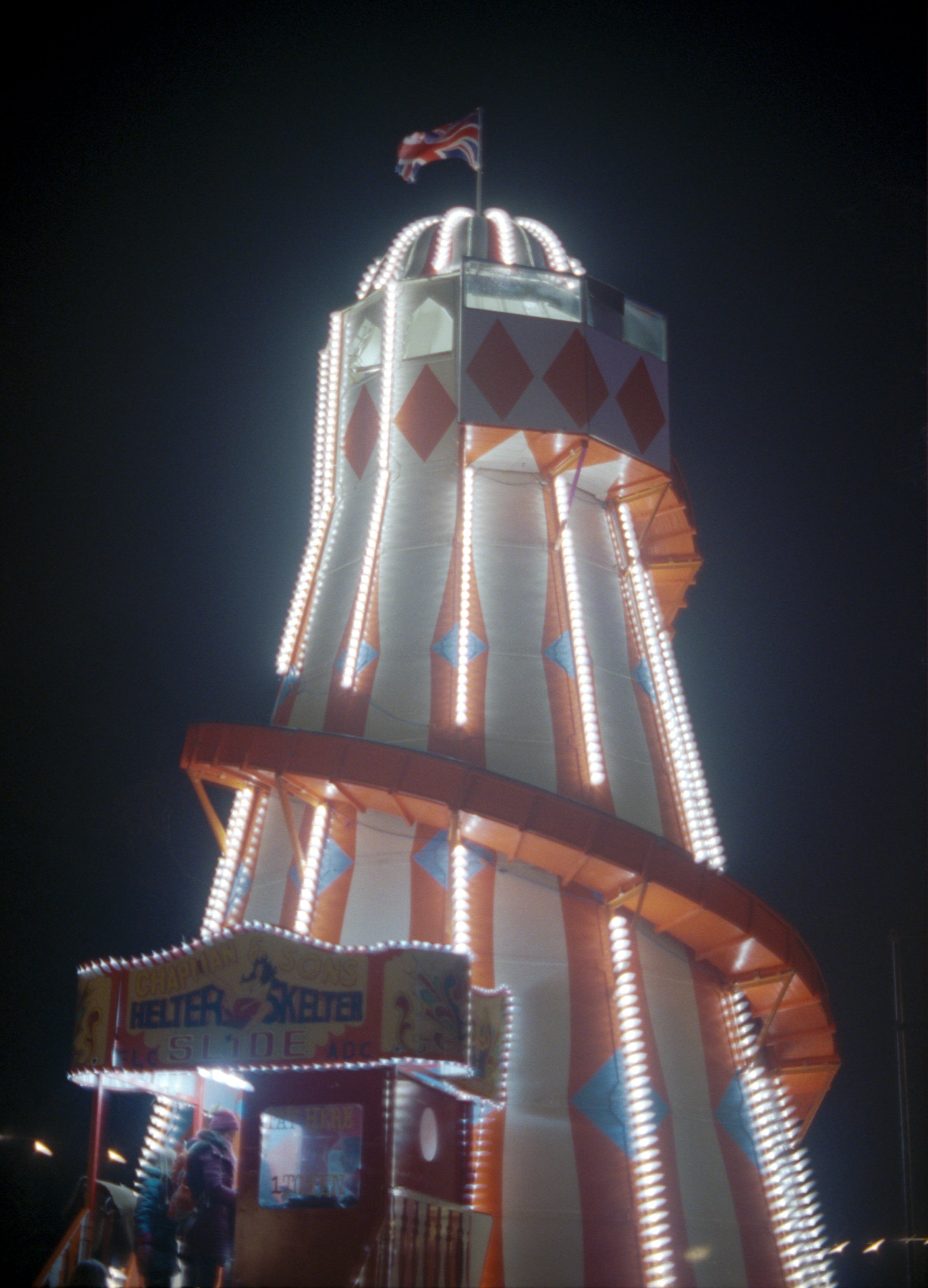 Decorative tower with lights and a flag at night